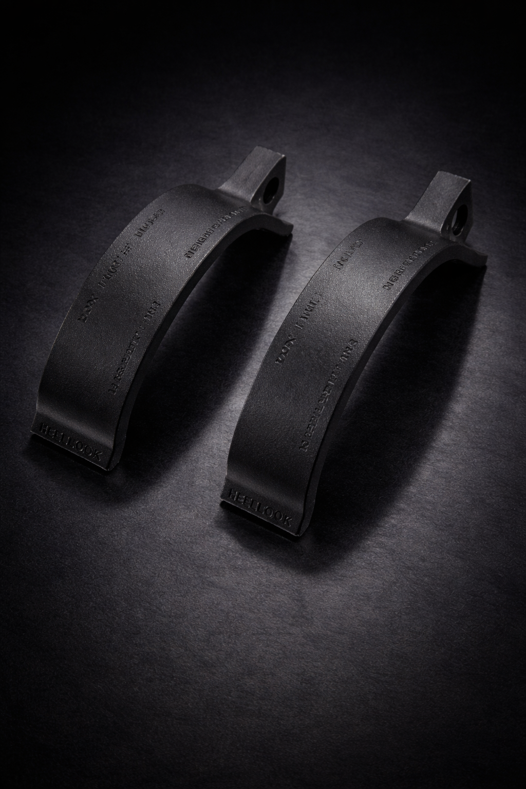 Two black leather straps on a dark textured surface